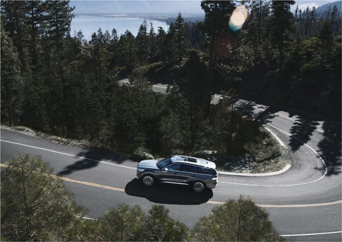 A 2023 Lincoln Aviator® SUV is being driven on a winding mountain road | Mike Reichenbach Lincoln in Florence SC